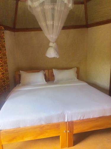 a bedroom with a bed with white sheets and a window at New Court View Hotel in Masindi