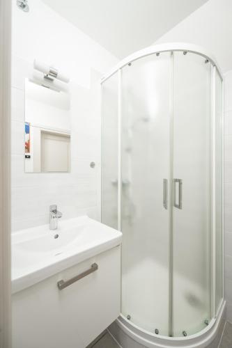 a white bathroom with a shower and a sink at Bedřichov U Nás in Bedřichov