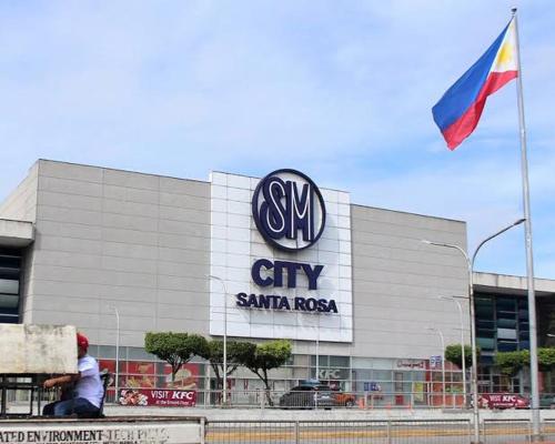 a man sitting on a bench in front of a car dealership at SMDC PARK RESIDENCE SM City Santa Rosa, Laguna in Ibaba
