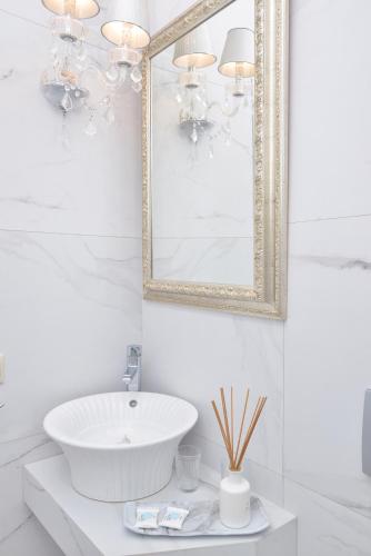 a white bathroom with a sink and a mirror at Epavlis Luxury apts in Leptokaria