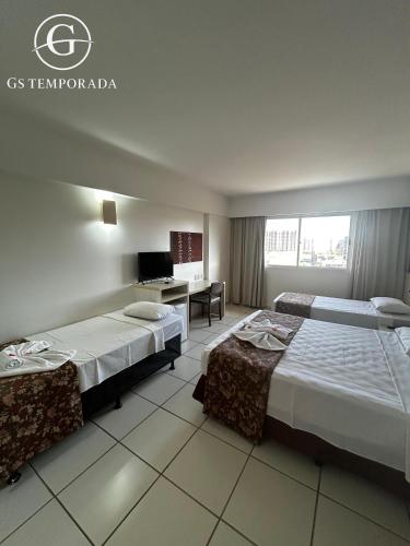 a hotel room with two beds and a desk at Hotel suits Le jardin in Caldas Novas