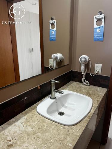 a white sink in a bathroom with a mirror at Hotel suits Le jardin in Caldas Novas