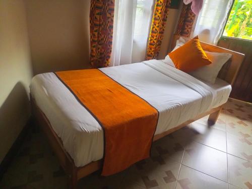 a bedroom with a bed with an orange blanket on it at New Court View Hotel in Masindi