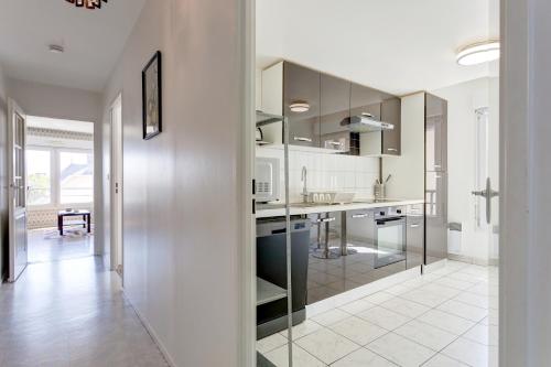 a kitchen with stainless steel cabinets and a white floor at Le cocon Champenois-Parking, centre & Tram in Reims