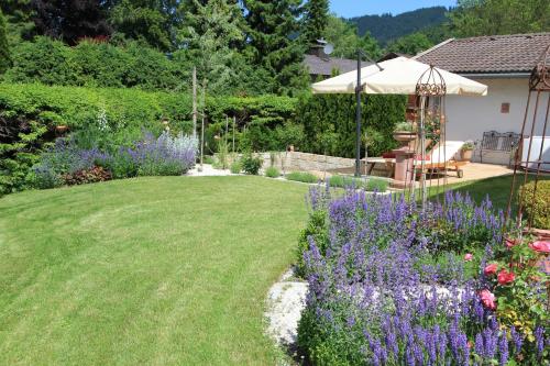 a garden with purple flowers and an umbrella at Villa Montelago in Rottach-Egern