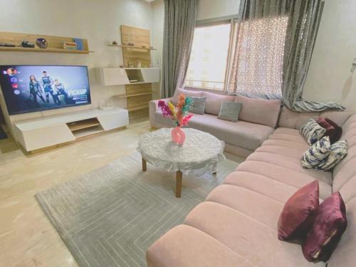 a living room with a pink couch and a tv at Luxury résidence Taj Nouaceur in Nouaseur