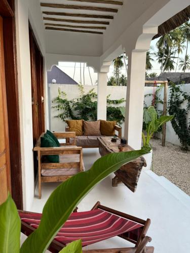 Kumba UremboにあるVilla Kahawa Zanzibarの家の中に椅子とソファーがあるポーチ