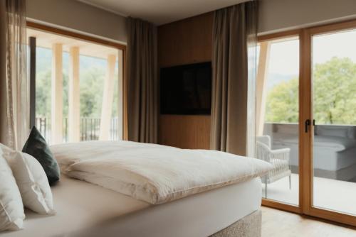 a bedroom with a white bed with a balcony at Hotel B&B Feldmessner in Brunico