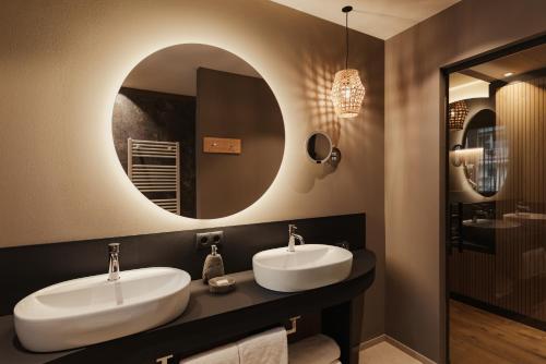 a bathroom with two sinks and a mirror at Hotel B&B Feldmessner in Brunico