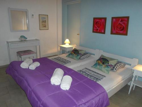 dwa łóżka w pokoju z fioletowymi prześcieradłami i różami w obiekcie Villa Leena w mieście Paramonas