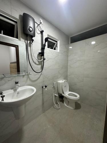 a bathroom with a sink and a toilet and a tv at Nallur Heritage Villa in Jaffna