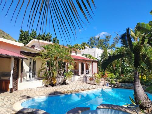 a villa with a swimming pool in front of a house at Tamarin chambre d'Hôtes in Tamarin