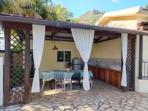 a patio with a table with chairs and a kitchen at Tamarin chambre d'Hôtes in Tamarin