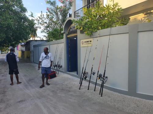 two men standing in front of a building with golf sticks at Oceanic Inn in Kolamaafushi
