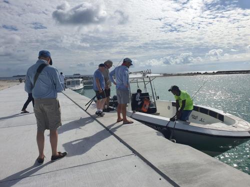 a group of men standing on a dock next to a boat at Oceanic Inn in Kolamaafushi