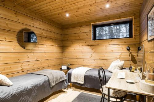 two beds in a room with wooden walls at Stay North - Utsunkajo in Kittilä