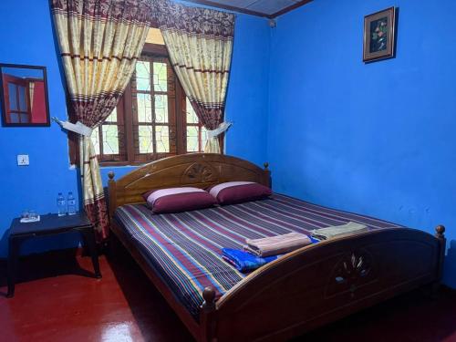 a bedroom with a bed with blue walls and a window at Pink House Ella in Ella