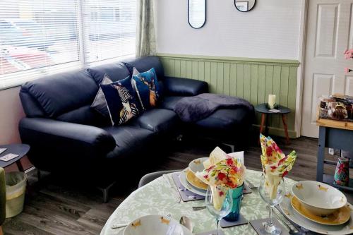 a living room with a black couch and a table at Chalet Ty Lilli Wen -Sleep 6- Pet friendly in Kidwelly
