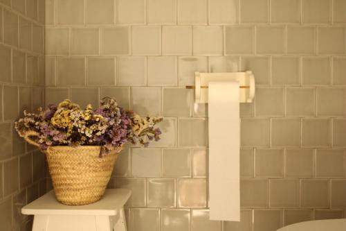 a basket of flowers sitting on a toilet in a bathroom at Escola da Boavista in Melides