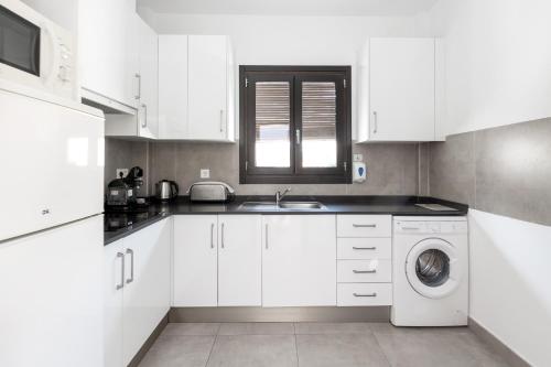 a white kitchen with a sink and a washing machine at Nest Flats Granada in Granada