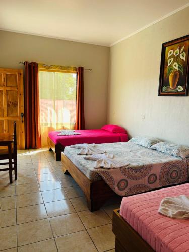 a bedroom with three beds and a window at Hotel La Fiore de Bahia in Uvita