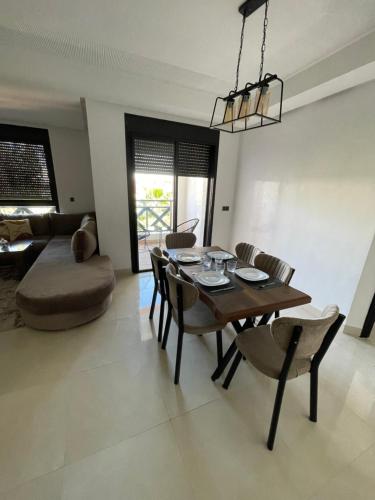 a dining room with a table and chairs and a couch at Appartement cosy Marrakech in Marrakech