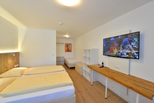 a bedroom with two beds and a flat screen tv on the wall at Hotel Garni Pension Gambrinus in Passau