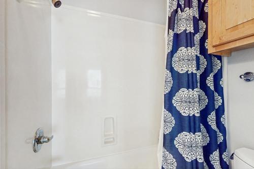 a bathroom with a shower with a blue and white shower curtain at Molokai Villas 5B in Pensacola