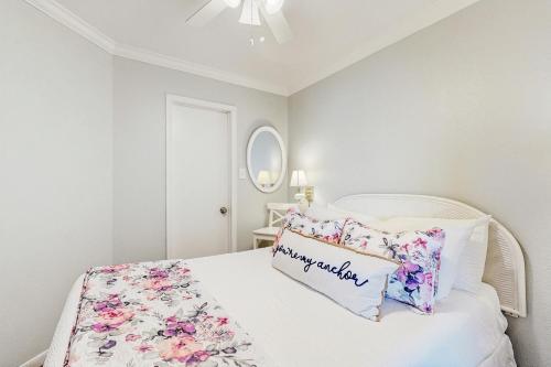 ガルベストンにあるThe Victorian Condos - Beach Wavesの白いベッドルーム(花柄の枕付きのベッド付)