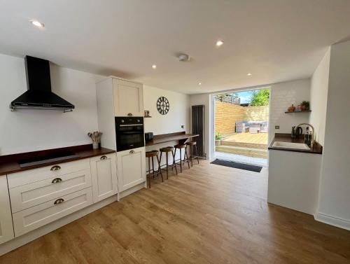 a kitchen with white cabinets and a wooden floor at Olive Tree Brighton-Bright & Spacious 4 bedroom home with Garden & Free parking in Brighton & Hove
