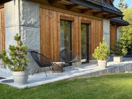 a patio with two chairs and trees in front of a house at Kama Lama in Zakopane