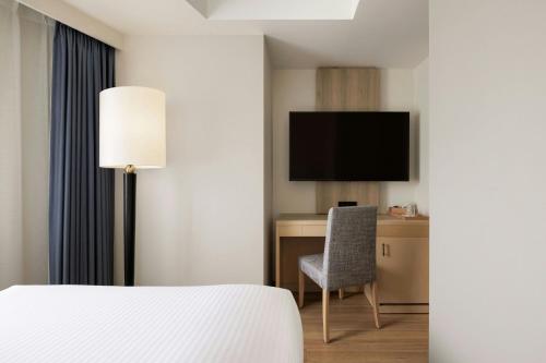 a hotel room with a bed and a desk and a tv at Fairfield by Marriott Sapporo in Sapporo