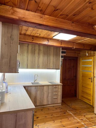 a kitchen with wooden cabinets and a wooden floor at Domki Pod Lasem in Macharce