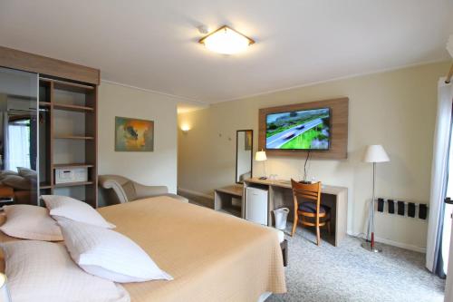 a hotel room with a bed and a desk at Pousada Villa Capivary Campos do Jordão in Campos do Jordão