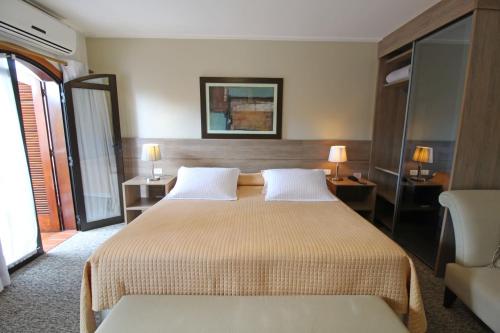 a hotel room with a bed and a chair at Pousada Villa Capivary Campos do Jordão in Campos do Jordão