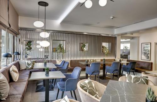 a restaurant with couches and tables and chairs at Leonardo Hotel Muenchen City West in Munich