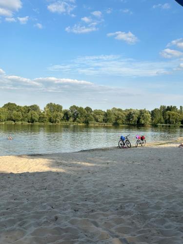 two bikes parked on a sandy beach next to a river at GREENMIST apartaments in Kyiv