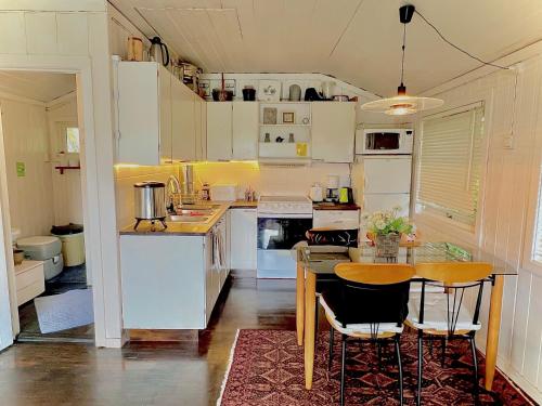 una cucina con mobili bianchi, tavolo e sedie di Cabin at Hestsjøen Badeplass a Trondheim