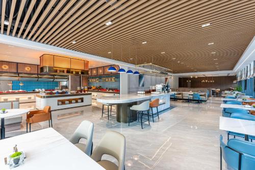 a restaurant with tables and chairs in a cafeteria at Holiday Inn Express Taizhou Jiaojiang in Taizhou