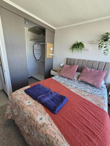 una camera da letto con un letto grande con due cuscini blu di Céntrico 2 habitaciones camas matrimoniales -1 baño parking privado calefacción AC a Rancagua