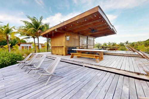 a deck with chairs and a table and a building at Seabird Villa 23 in Placencia Village