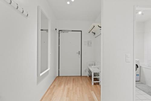 a white room with a door and a wooden floor at Balcony Apartment I Direct connection to the Airport in 15 Min in Vienna