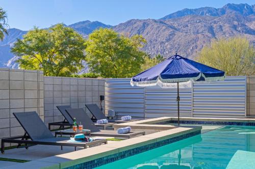 an umbrella and lounge chairs next to a swimming pool at Royal Escape by ACME House Company in Palm Springs