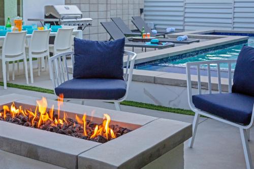 two chairs and a fire pit next to a swimming pool at Royal Escape by ACME House Company in Palm Springs
