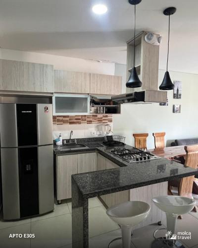 a kitchen with a refrigerator and a counter with stools at Alojamiento Familiar para 40 - Con 4 Piscinas - 3 Jacuzzi - Sauna - By Molca Travel in Armenia