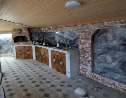 una cocina con armarios de madera y una pared de ladrillo en Melek villa, en Gabala