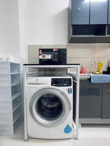 a kitchen with a washing machine under a counter at Premier Suites KLCC By Majestic Residence in Kuala Lumpur