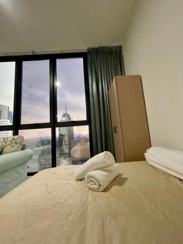a bed with a towel laying on it in a room with a window at Premier Suites KLCC By Majestic Residence in Kuala Lumpur