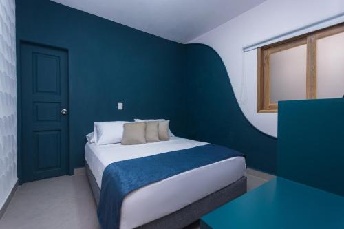 a bedroom with a bed with a blue accent wall at Hotel Chromatic in Guatapé