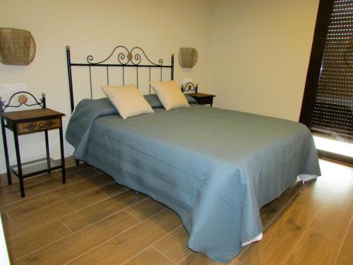 a bedroom with a blue bed with two pillows at Casa Rural El Parque in Navalcán